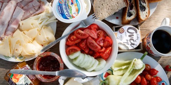 Delicious breakfast setup with cheese, cold cuts, bread, and fresh vegetables.