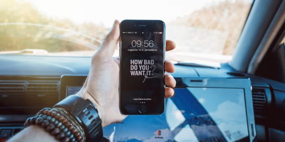 Close-up of a hand holding a smartphone in a car, highlighting technology and motivation.